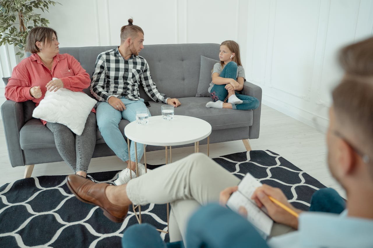 Family therapy session featuring parents and child with therapist in a cozy office setting.