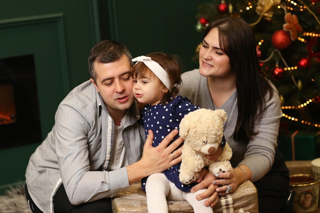 a-man-woman-and-child-sitting-in-front-of-a-christmas-tree-mwxnqg84vr0